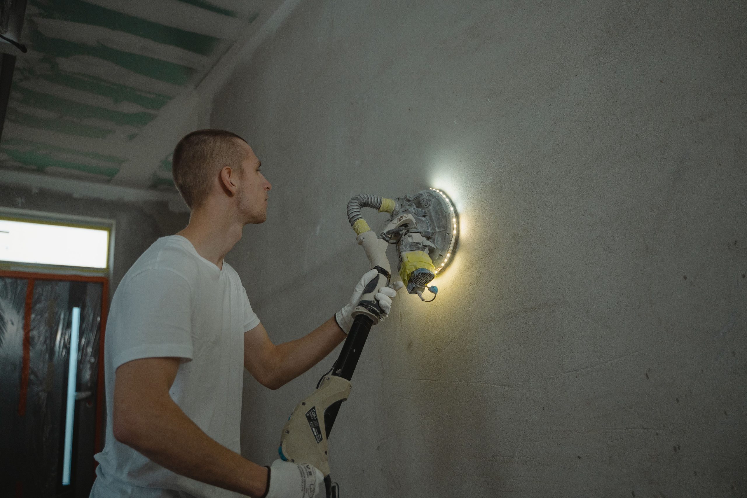 Homme poncant mur intérieur lors rénovation