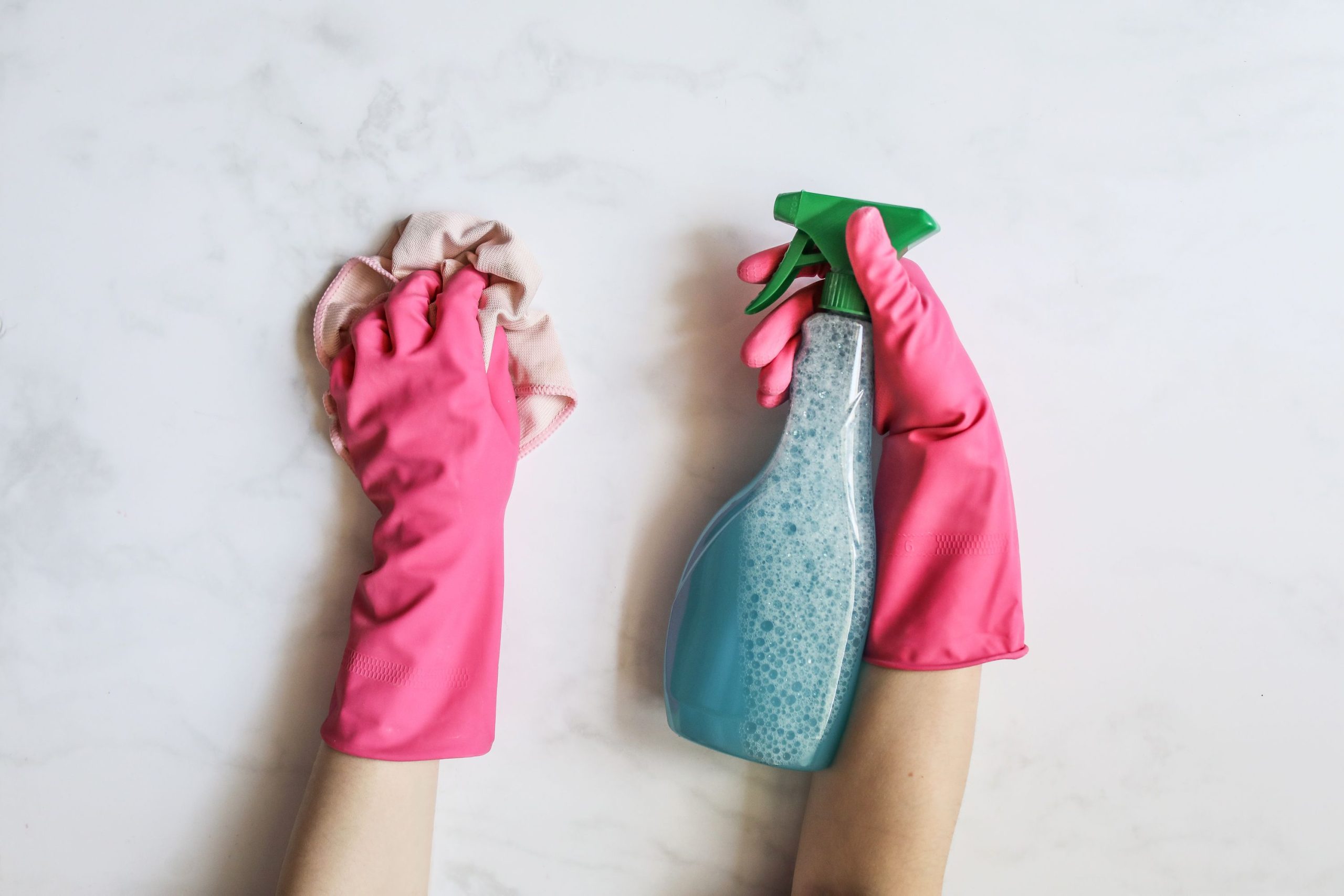 Mains gantées roses nettoyant avec un spray