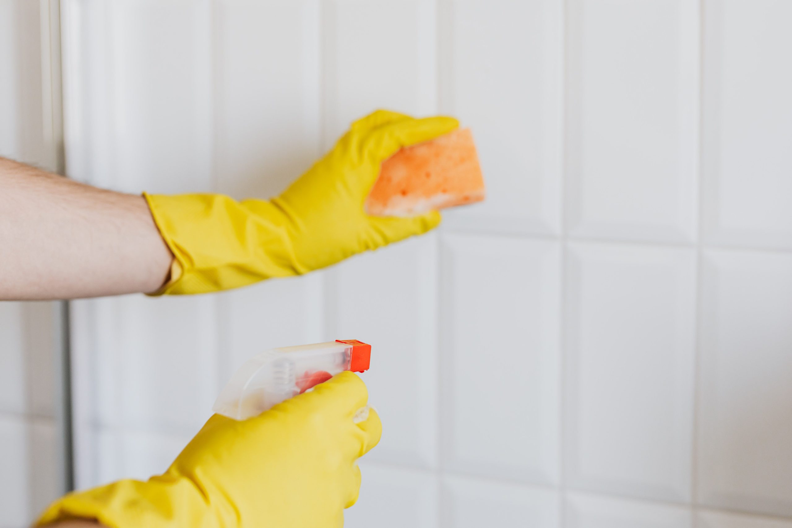 Femme nettoyant un carrelage avec spray et éponge